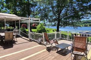 una terrazza in legno con sedie, tavolo e tenda di Spacious Lakefront - Remodeled, Views & All Amenities Included a Skaneateles