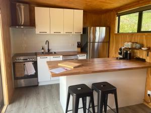 a kitchen with a counter and two stools in it at White Pine Bush Cabins in Otangihaku
