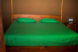 a green bed with two green pillows on it at Milla Resort in Buttala