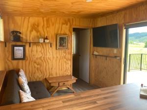 a living room with a couch and a table and a tv at White Pine Bush Cabins in Otangihaku