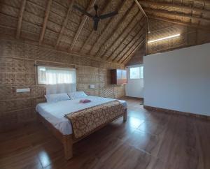 a bedroom with a bed in a room with wooden floors at Mowgli's Cafe Hampi & Guest House in Hampi