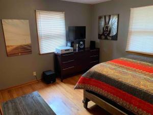 Schlafzimmer mit einem Bett und einer Kommode mit einem TV in der Unterkunft Whole Home MidCentury - Quiet & Close to Downtown in Des Moines