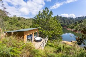 una cabaña en una colina junto a un cuerpo de agua en Cabañas Refugio Himalaya, en Guatapé