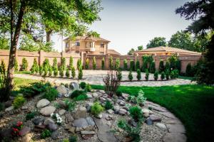 a garden in front of a house with a fence at Assol Hotel in Taganrog