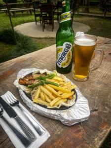 ein Sandwich und Pommes Frites und ein Bier auf dem Tisch in der Unterkunft Hotel Tharu Garden, Sauraha in Sauraha