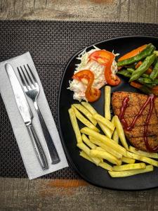 a black plate with meat and french fries and vegetables at Hotel Tharu Garden, Sauraha in Sauraha
