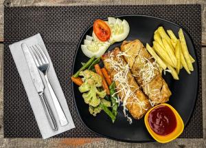 un piatto nero di cibo con panino e patatine fritte di Hotel Tharu Garden, Sauraha a Sauraha