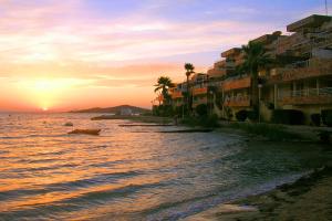 een strand met gebouwen en palmbomen bij zonsondergang bij Ona Marina Arpón in La Manga del Mar Menor