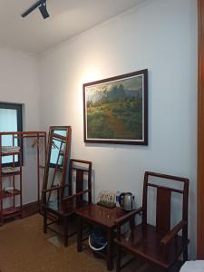 um quarto com três cadeiras de madeira e uma pintura na parede em An Homestay & Hostel em Cao Bang