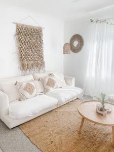 a white living room with a white couch and a table at Beach Bungalow Yeppoon in Yeppoon