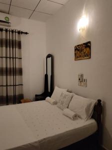 um quarto com uma cama com lençóis brancos e almofadas em Sky Galaxy Homestay em Dickwella