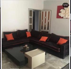 een woonkamer met een zwarte bank en oranje kussens bij joli appart F2 de 80m2 à liberté 6 extension in Dakar