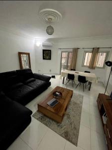 een woonkamer met een zwarte bank en een tafel bij joli appart F2 de 80m2 à liberté 6 extension in Dakar