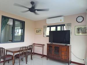 ein Wohnzimmer mit einem TV und einem Esstisch in der Unterkunft Seaview Eagles Nest Apartments in Rawai Beach