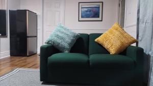a green couch with two pillows on it in a living room at Comfy Rooms & Studio in 3Bed Home in Timberlea