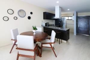 eine Küche und ein Esszimmer mit einem Holztisch und weißen Stühlen in der Unterkunft Departamento de lujo con vista al Mar y a 1 cuadra del Malecón - Flamingo 601 in Mazatlán