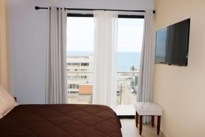 Schlafzimmer mit einem Bett und einem großen Fenster mit Meerblick in der Unterkunft Departamento de lujo con vista al Mar y a 1 cuadra del Malecón - Flamingo 601 in Mazatlán