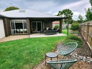 a yard with two chairs and a patio at Goodenia Vibes in Inverloch