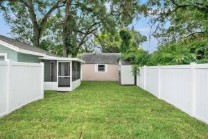een achtertuin met een wit hek en een huis bij Comfy Modern Farmhouse Cottage w/ Private Patio! in Tampa