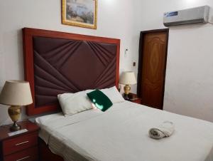 a bedroom with a large bed with a large headboard at Homewood Suites Family Guest House & Apartments in Lahore