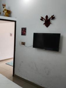 TV de pantalla plana colgada en una pared blanca en Homewood Suites Family Guest House & Apartments, en Lahore