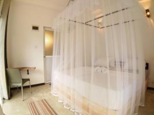 a bedroom with a bed with white curtains at Hello Whites in Ahangama