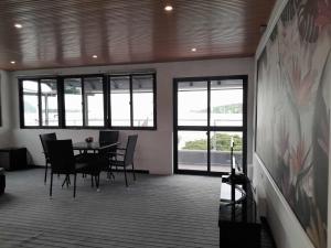 Crystal Beach Hotel في بورت فيلا: غرفة طعام مع طاولة وكراسي ونوافذ