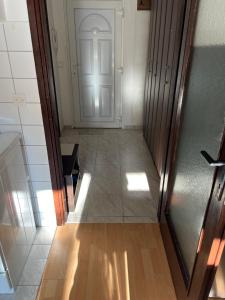 un corridoio vuoto con porta bianca e pavimento in legno di Studio apartman Dora a Vinkovci
