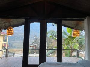 een slaapkamer met uitzicht op de bergen door een raam bij La Maison SAPA - Bungalows in Sa Pa