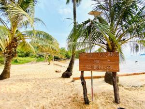 a sign on a beach with palm trees at Koh Rong 71 Guesthouse in Koh Rong Island