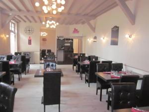 a dining room with tables and chairs and a clock at Le C Gourmand in Sées