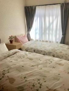 Un dormitorio con dos camas y una ventana. en ZY House, en Osaka