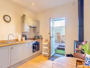 a kitchen with white cabinets and a table and a patio at Rose Cottage - Uk45497 