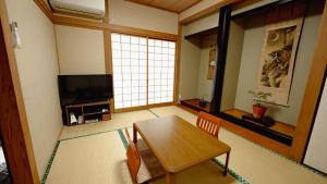 a living room with a wooden table and a television at AMAMI-Green-Garden in Amami