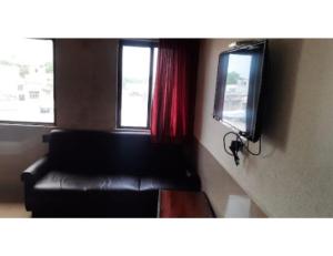 sala de estar con sofá negro y TV en Hotel Janki Guest House, Jamnagar, en Jamnagar