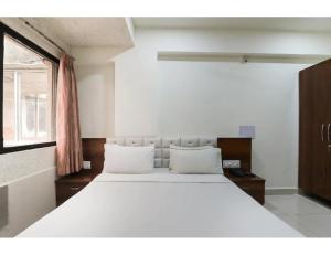 1 cama blanca grande en una habitación con ventana en Hotel Janki Guest House, Jamnagar, en Jamnagar