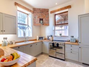 una cucina con armadi bianchi e un cesto di frutta su un bancone di Garden Cottage - Uk45498 