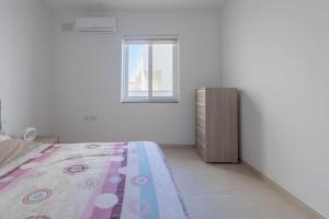 een slaapkamer met een bed en een raam bij Full Air-conditioned, 2 Bedroom Apt. in Żejtun