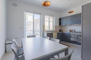 een keuken met een witte tafel en een aantal stoelen bij Full Air-conditioned, 2 Bedroom Apt. in Żejtun