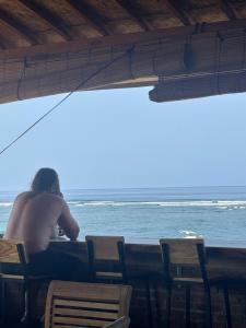 Un homme sans vaisseau assis à une table près de l'océan dans l'établissement Lakey Peak B and B, à Huu