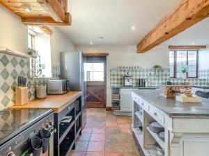 una gran cocina con electrodomésticos de acero inoxidable y techos de madera. en Eaton Barn - Uk45499 