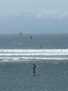 a person standing on a beach with kites in the ocean at Lakey Peak B and B in Huu