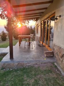 een patio met een tafel en stoelen en de zonsondergang bij Berghouse and Cottages in Langkloof