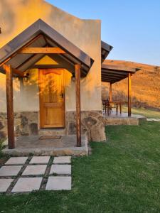 a house with a wooden door and a table at Berghouse and Cottages in Langkloof