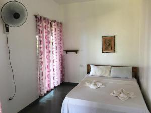 1 Schlafzimmer mit 2 Betten mit rosa Vorhängen und einem Ventilator in der Unterkunft Tori's Backpacker's Paradise in Siquijor