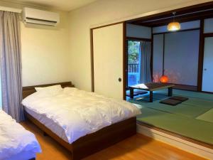 a bedroom with a bed and a room with a table at 南箱根 熱海 貸切別荘 リゾートハウス トモ in Atami