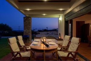 a wooden table and chairs on a patio at Cristelia seafront & pool villa in Lakhania