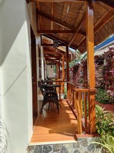 un porche de madera con mesa y sillas. en Glorias Panglao Inn 1 en Panglao City