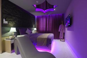 um quarto roxo com uma cama com iluminação roxa em Chiic House 1 - Khách sạn tình yêu em Da Nang
