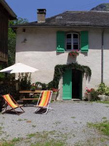two chairs and an umbrella in front of a house at Bouerzy in Laruns